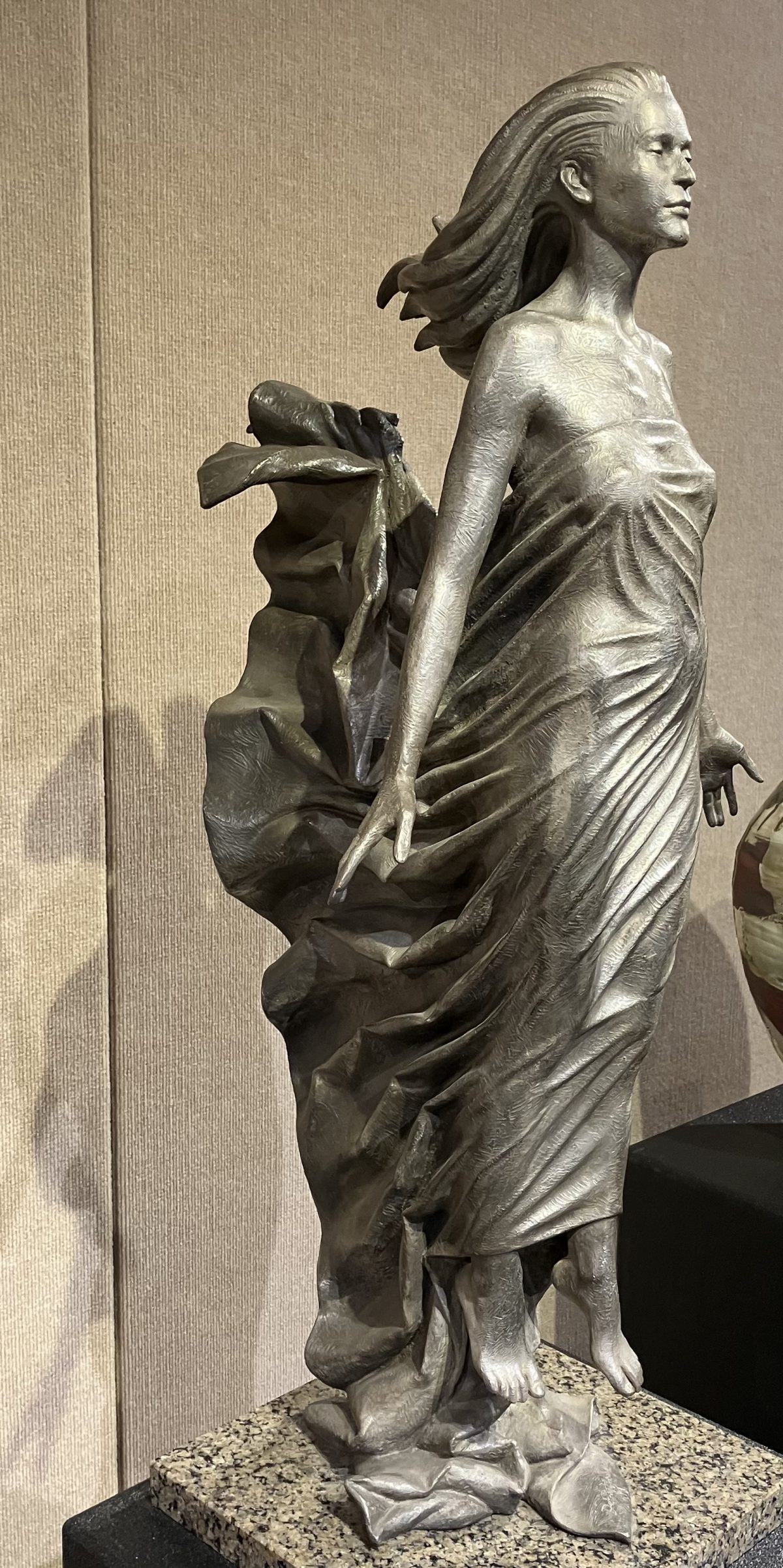 Bronze sculpture titled 'Ascension' depicting a woman in flowing robes, standing with an upward gaze, symbolizing elevation and grace.