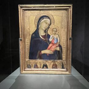 A framed painting of the Madonna and Child, set against a gold-leaf background, displayed in a museum exhibit.