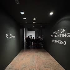 Entrance to the exhibition Siena: The Rise of Painting 1300-1350, featuring a dark hallway leading into the museum gallery.