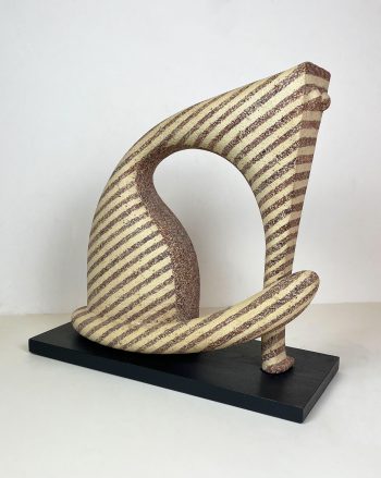 A ceramic sculpture featuring a swirling abstract form with brown diagonal stripes on a cream-colored surface, displayed on a black platform.
