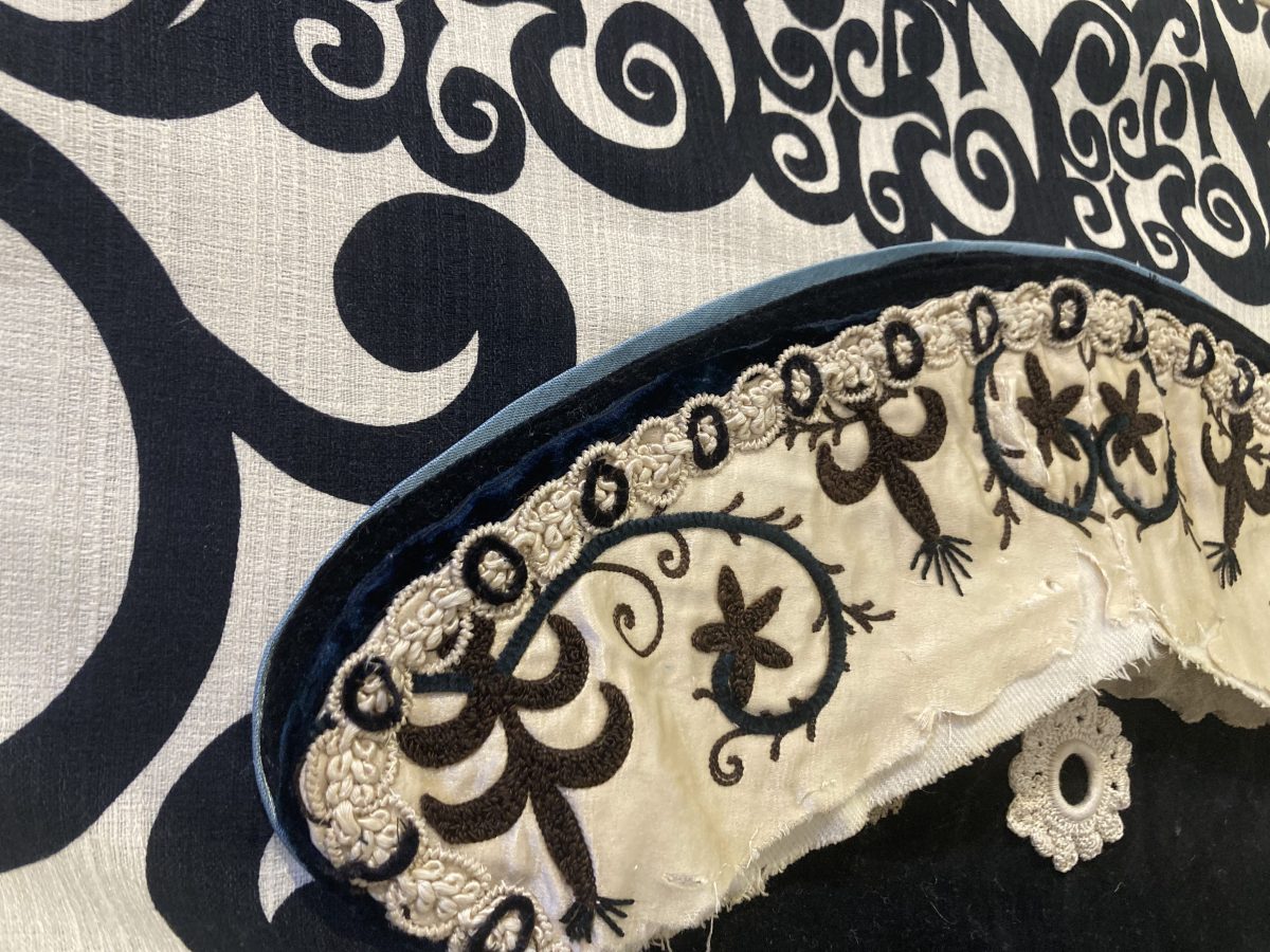 Close-up of a vintage appliqué pennant by Fern & Reed, showing intricate floral embroidery and layered textile textures.