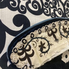 Close-up of a vintage appliqué pennant by Fern & Reed, showing intricate floral embroidery and layered textile textures.