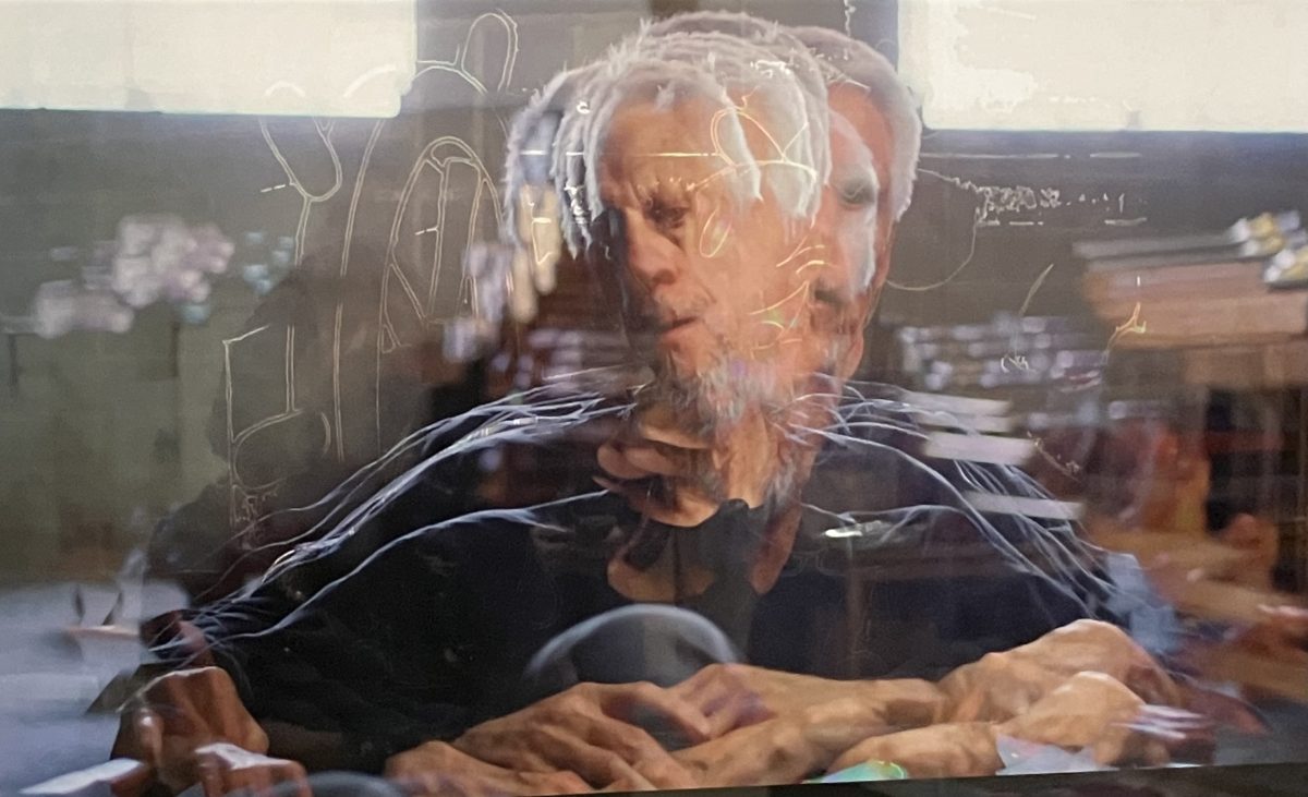 Photographic portrait showing overlapping exposures of a man’s face and hands, producing a blurred, ghostlike effect.