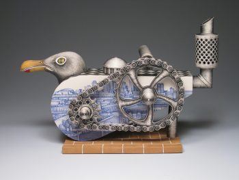 A detailed ceramic sculpture of a seagull with gears, pipes, and a chain integrated into its body, painted in blue and metallic tones with a cityscape motif.